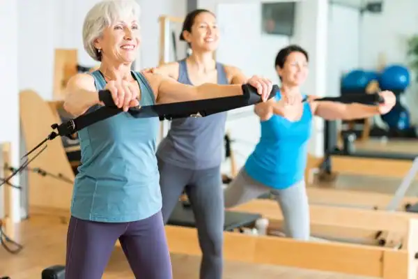 Toning Arms After 60: Empowering Womens Fitness Through Effective Weight Training 2 older woman doing weight training Walsall and resistance in the gym to tone upper arms